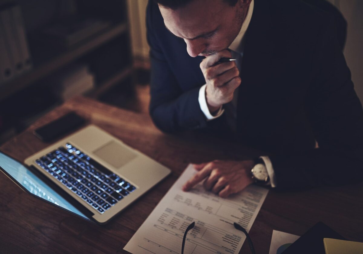 Man reviewing finances at a desk in front of laptop