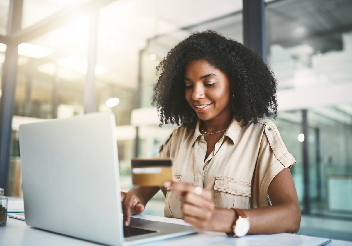 Woman holding a credit card while using a laptop