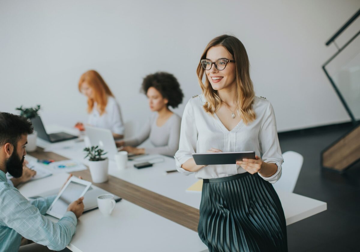 Businesswoman leaning against a table holding a tablet