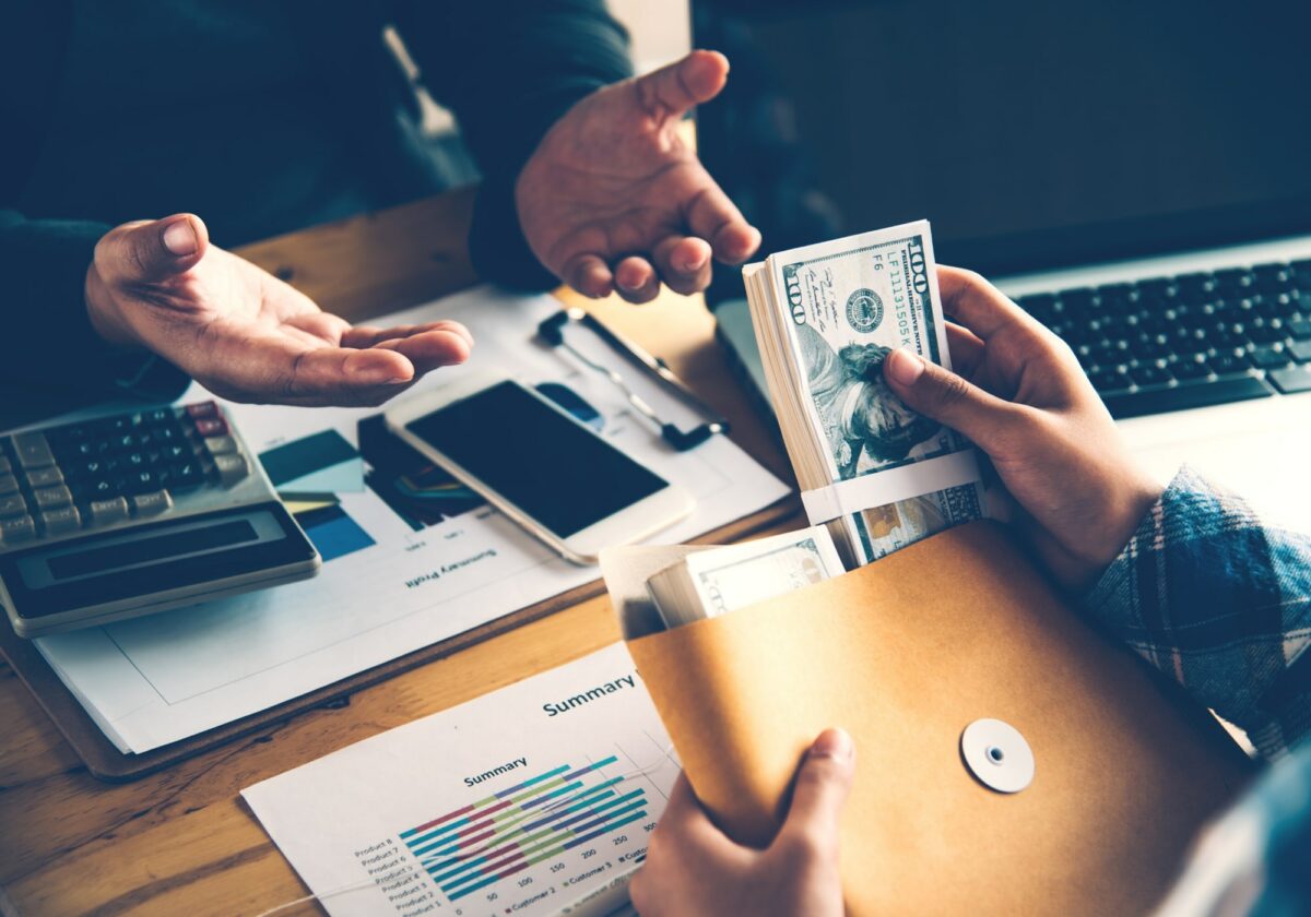 Two people discussing finances holding an envelope of cash