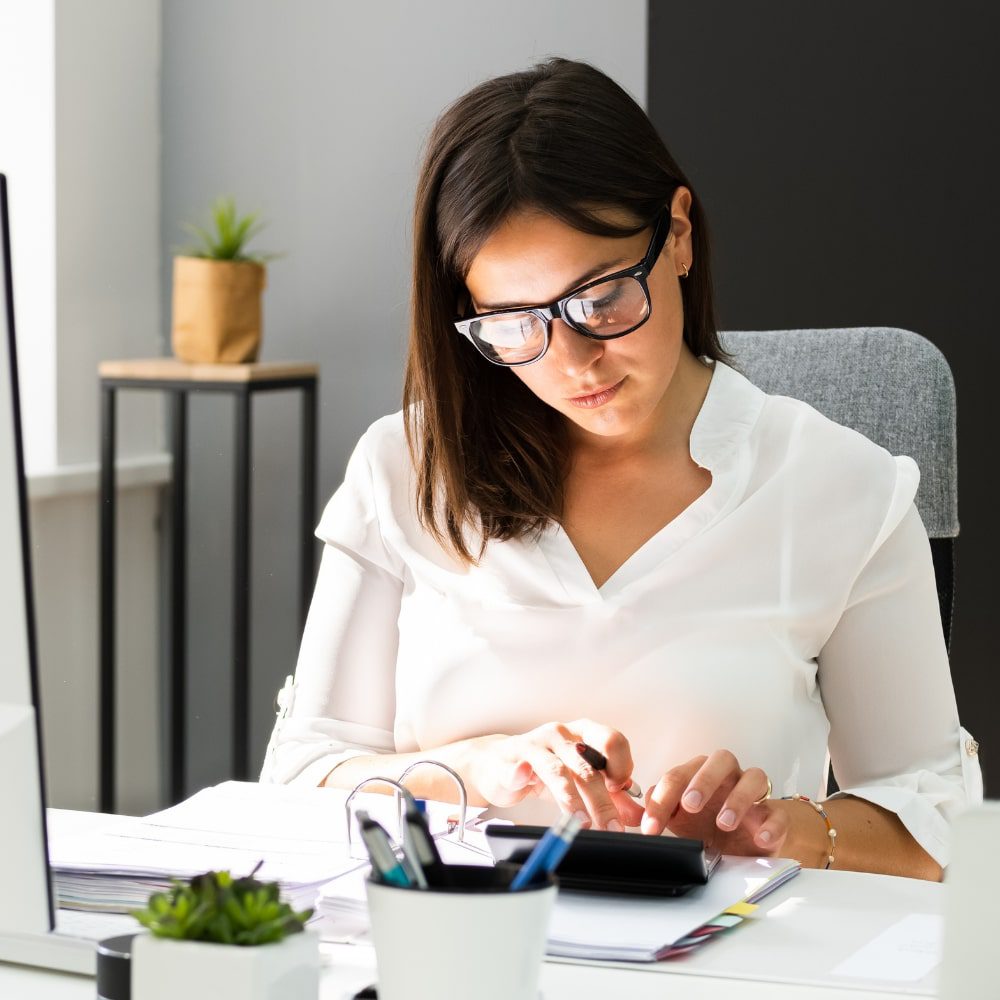 Women sitting using a calculator at desk