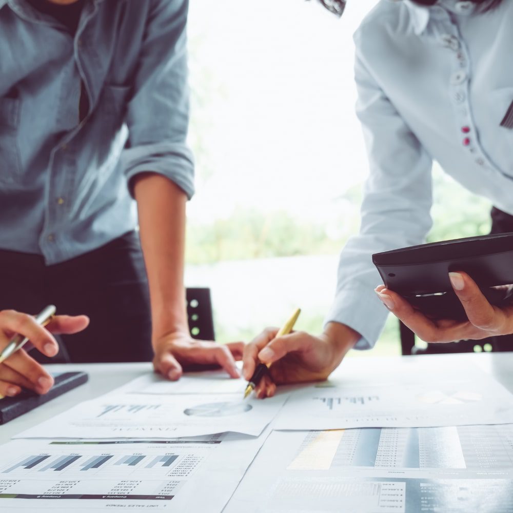 Two people reviewing business analytics while holding a calculator