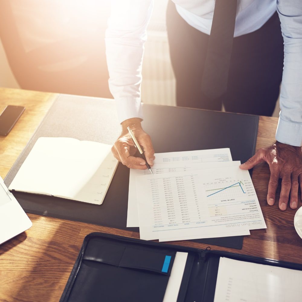 Man standing over desk writing on business documents