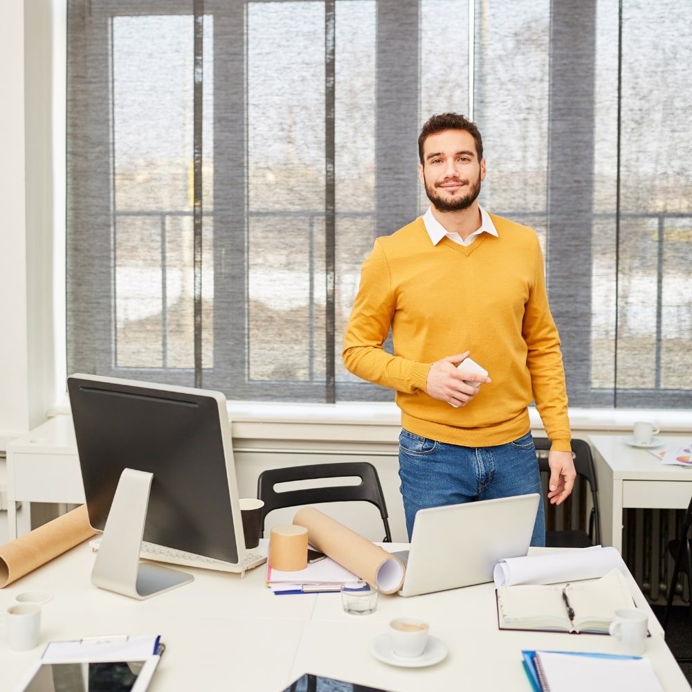 Business man stand above a table with comptuers