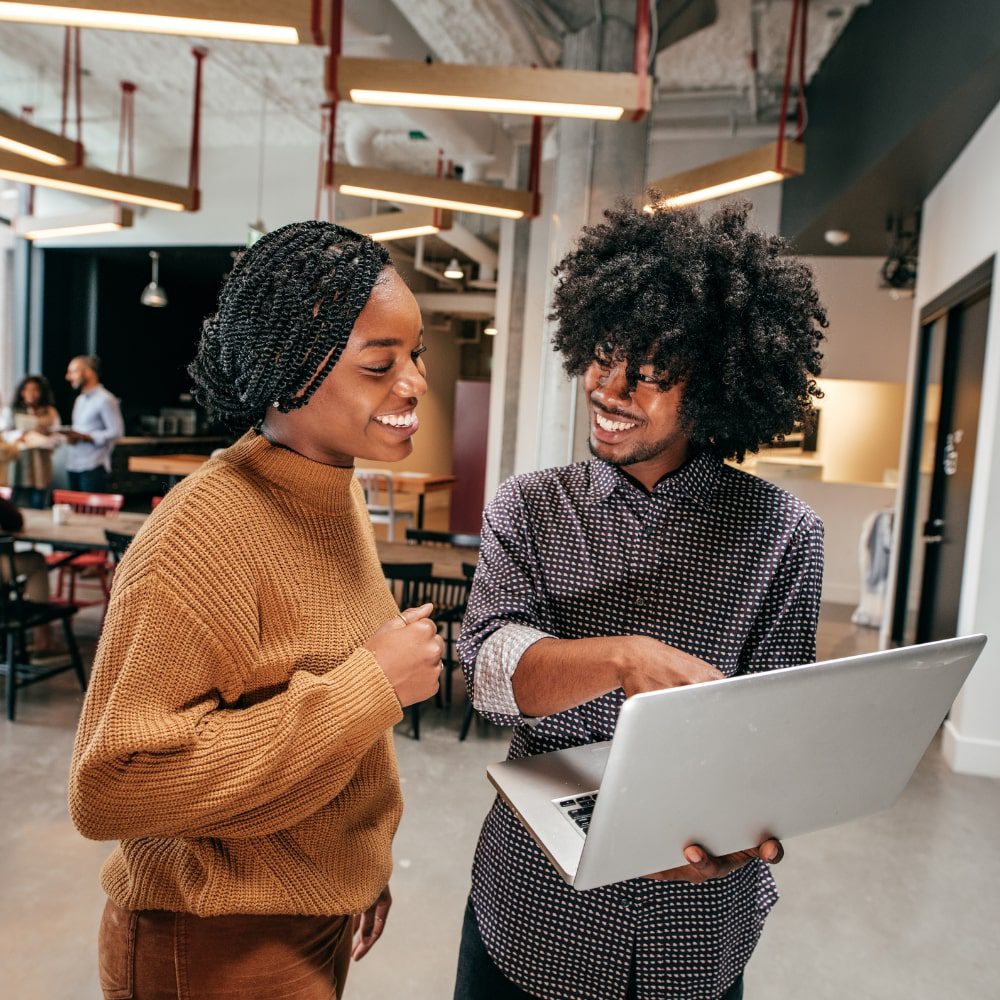 Two colleagues standing and looking at a laptop