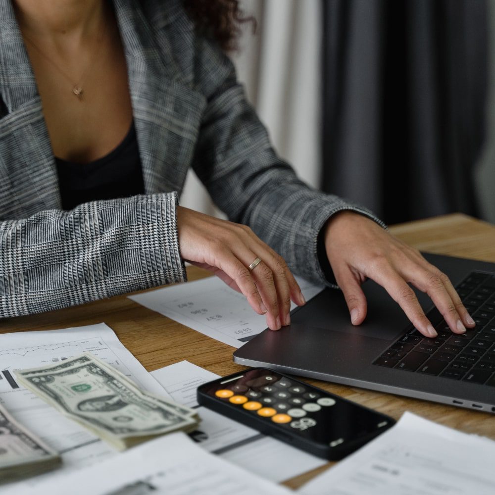 Woman working on a laptop while organizing money