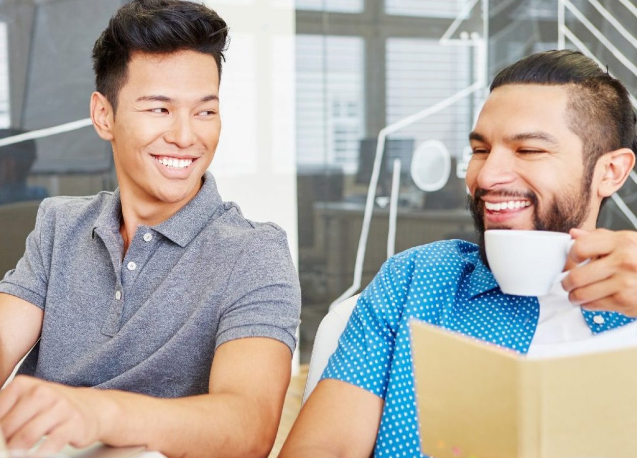 Two young men working on a computer and reading